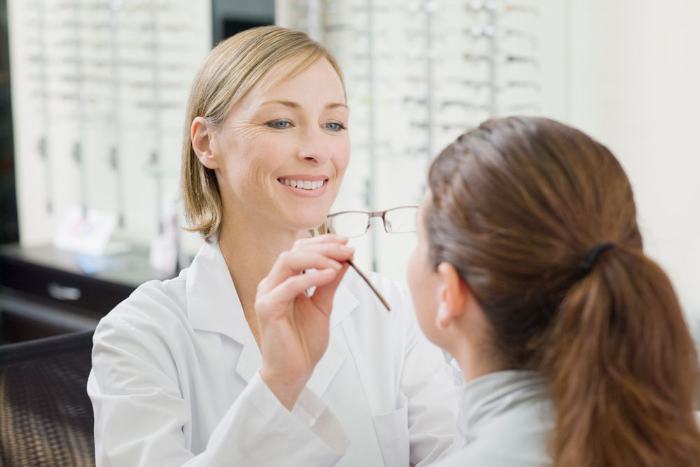 En kvinnlig optiker testar nya glasögon på en kund